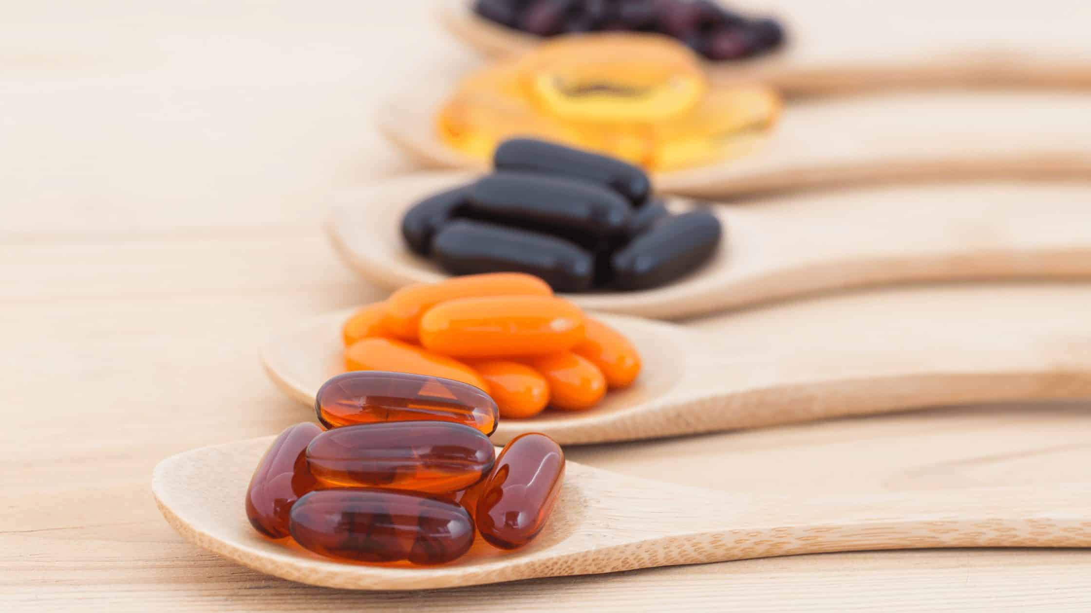 Multiple supplement pills organized on seperate wooden spoons